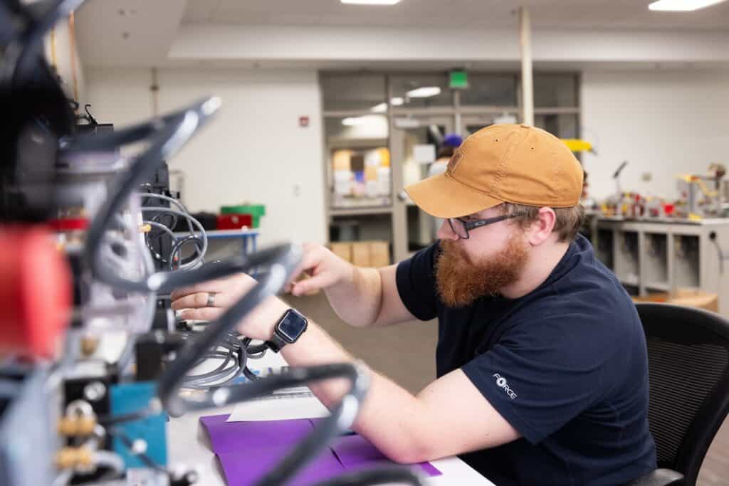 A University of North Alabama student adjusts wires attached to a machine.