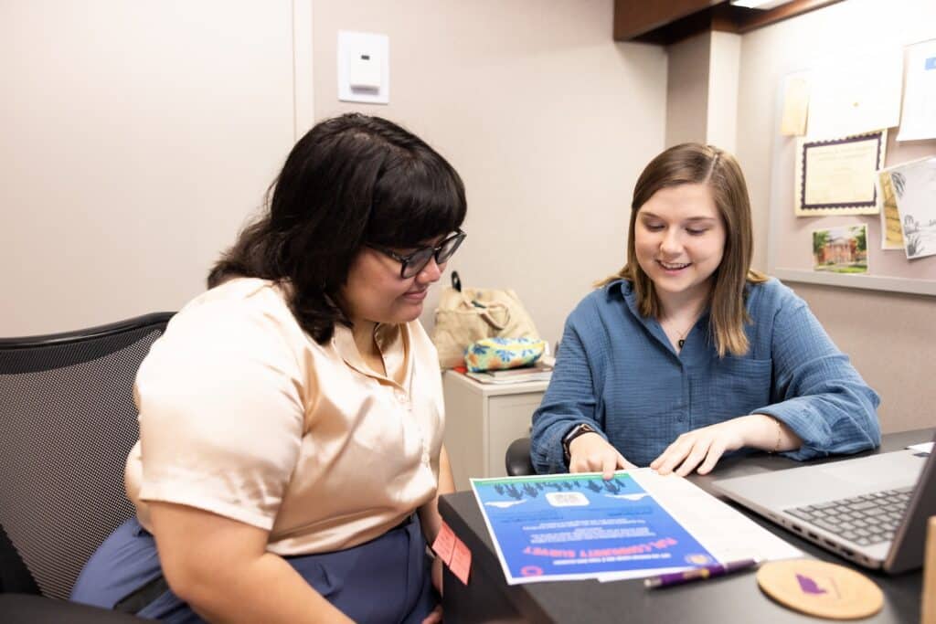 A University of North Alabama social work student discusses an opportunity on a flyer with a woman.