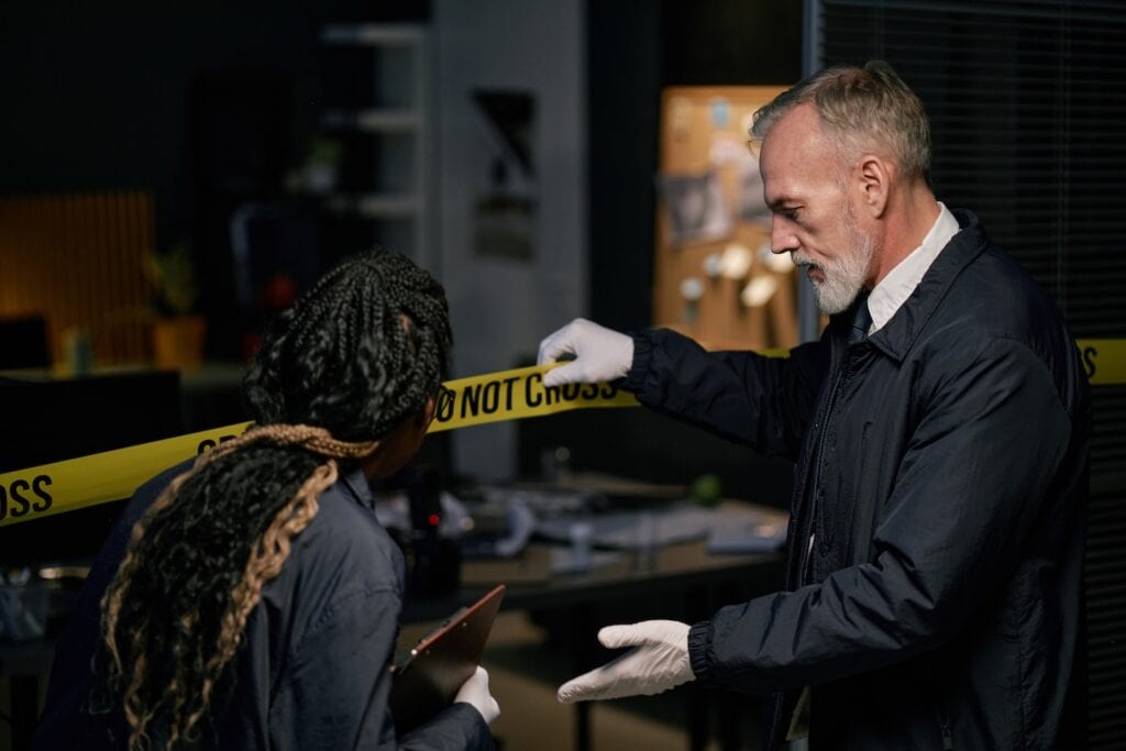 Investigators examine a crime scene with yellow tape.