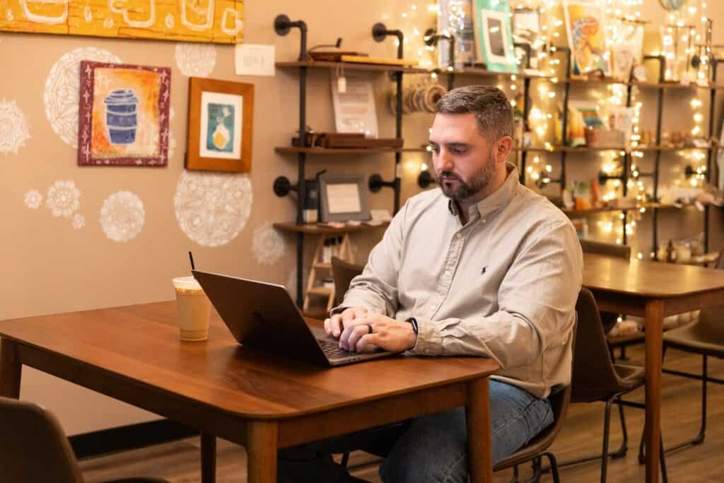 A University of North Alabama graduate student works on his laptop inside a coffee shop.